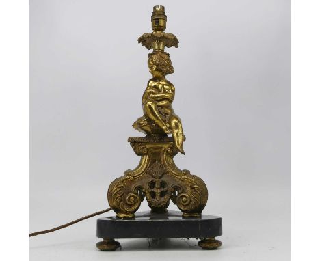 An early 20th century gilt brass table candle stick, having a single sconce surmounted by a seated girl on triform base and m