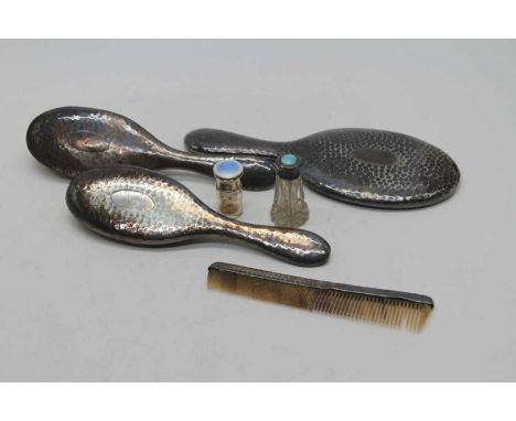 An Edwardian silver-clad brush set, comprising a mirror, two brushes and a comb, with hammer-beaten decoration, Birmingham 19