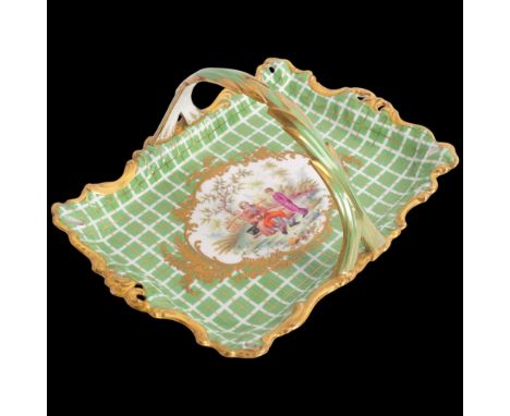 A 19th century porcelain basket, central painted panel depicting a man playing bagpipes, in textured gilded surround with gre