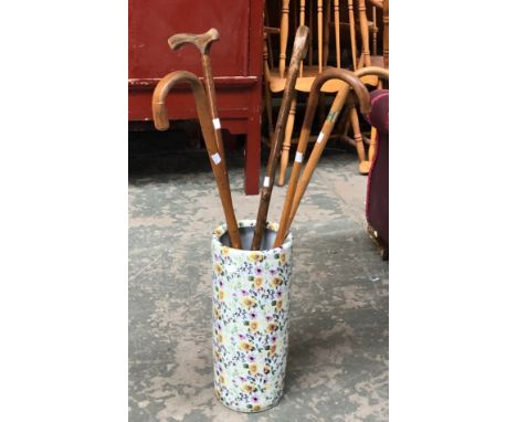 A floral ceramic stick stand containing five various walking sticks 