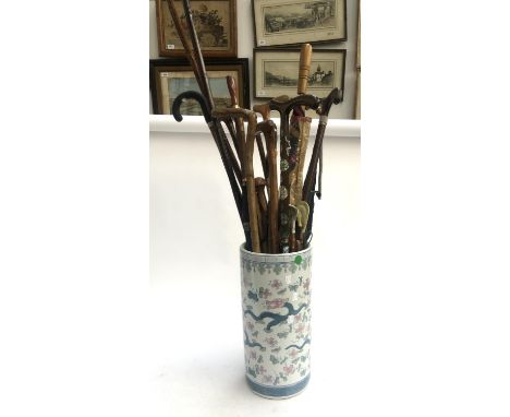 A Chinese ceramic stick stand decorated with dragons amongst flora, containing a quantity of walking sticks