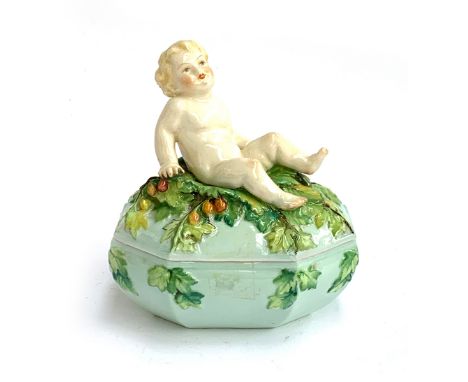 A rare early 20th century Royal Worcester porcelain box, modelled by Henri Bargas, the lid surmounted by a baby amongst sprin