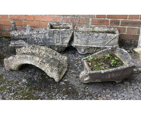 A composite stone train and tender planter, 121cm long overall, together with a small model of a bridge, and a wheelbarrow pl