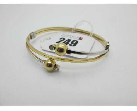 A Modern Two Colour Bangle, with ball and collet set highlights, stamped "585" (9grams). 