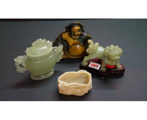 Four Chinese stone items, comprising: a tiger's eye 'flat-back' Buddha, 17cm wide; a celadon jade lion dog, 11cm wide, on fit