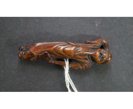 A Japanese carved wood netsuke, 19th century, of a tall bearded man with one hand behind his head, a fan in the other, 7.5cm 