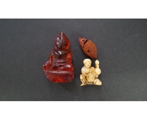 A Japanese carved ivory netsuke, Meiji period, of a kneeling man holding a double gourd, 4cm high; together with an amber sty