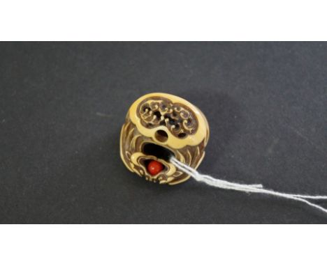 A Japanese carved ivory netsuke, Meiji period, of basket form, the handle formed as two opposing dragon heads clasping a red 
