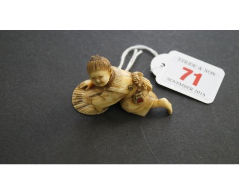 A Japanese carved ivory netsuke, Meiji period, of a small boy crawling over a fan, signed on tablet, 5cm long. Condition Repo