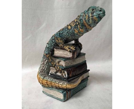 A ceramic Sculpture of a lizard on a pile of books with polychrome glaze, signed Jill Moger, 25.5cm high 