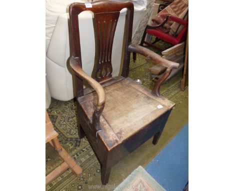 A Georgian Oak commode chair having a fret-worked back-splat, splayed arms and seat lifting to reveal a cream porcelain liner