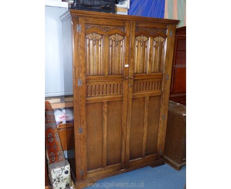 A contemporary Priory Oak style double Wardrobe having opposing doors with linen cold and fruiting vine door revealing an int