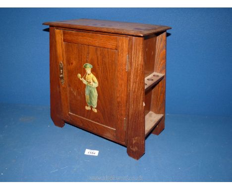 An Oak smoker's Cabinet with pipe racks to each side, with door stencil decorated with Dutch boy opening to reveal two drawer