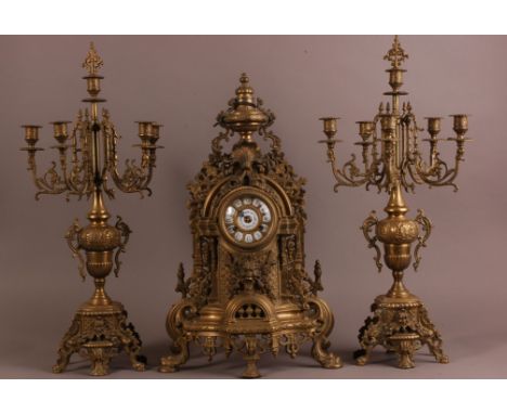 An early 20th century French brass clock garniture, having a pair of five branch candelabra with snuffers, 68cm, and the cloc