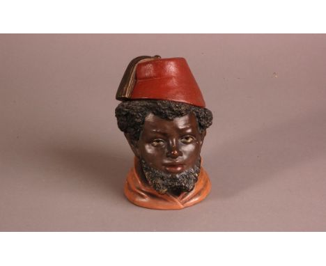 A late 19th century German ceramic figural tobacco jar, 14cm, modelled as young man in a fez