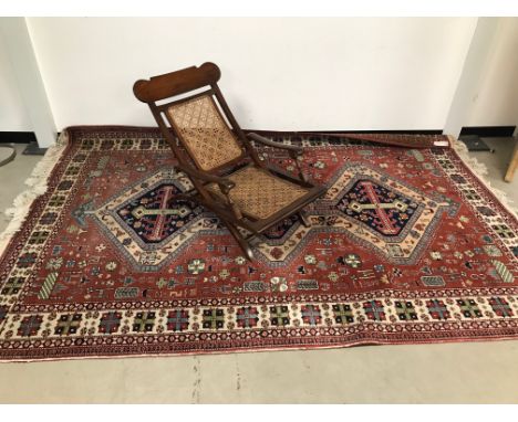 A vintage plantation chair, the folding hardwood frame with rattan seat and back, carpet not included