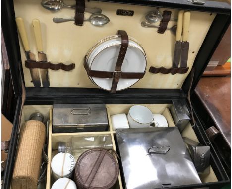 A vintage Brexton picnic hamper containing four place settings of plates with cups, canework covered flask, plain flask, vari