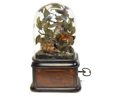 Glass domed singing birdcage automaton with three birds and a butterfly surrounded by faux paper foliage and a small mirrored