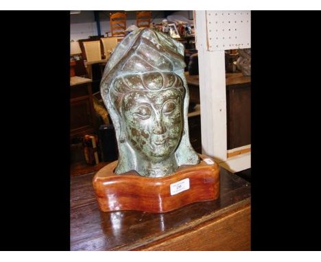 A bronze deity head on wooden stand - 31cm high 