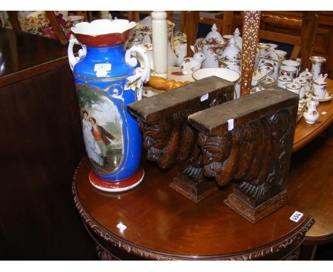A pair of carved oak shelf supports, alongside a double handled vase sporting walking couple scene - height 42cms 
