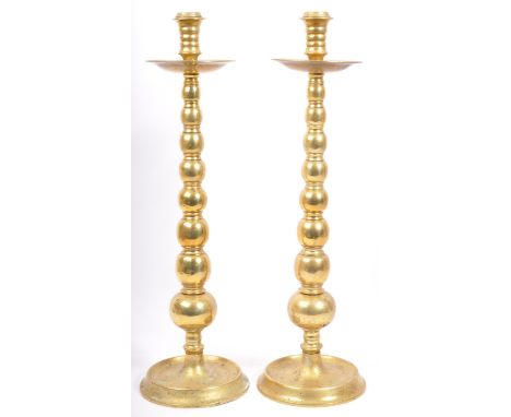 A pair of large 19th century brass candlesticks, each having bobbin turned effect to body and being raised on circular base. 