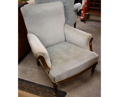An Edwardian mahogany framed armchair with light blue dralon upholsterey on carved fluted front legs with brass castors
