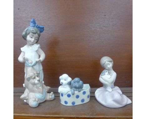 Three Nao figures; girl with soft toy, girl with puppy and two dogs in a basket, all boxed 