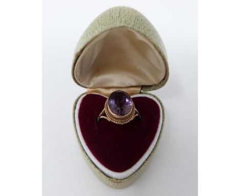 An antique 9 ct yellow gold and amethyst dress ring in a heart shaped vintage ring box. Set with an oval mixed cut amethyst i