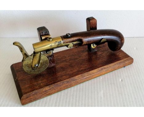 A 19th century eprouvette or gunpowder tester, the mahogany pistol grip with brass barrel, touch hole and calibration scale t