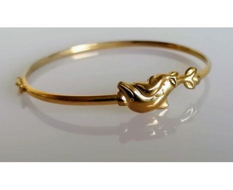 A yellow gold bangle with dolphin decoration, stamped 9kt, 4.33g