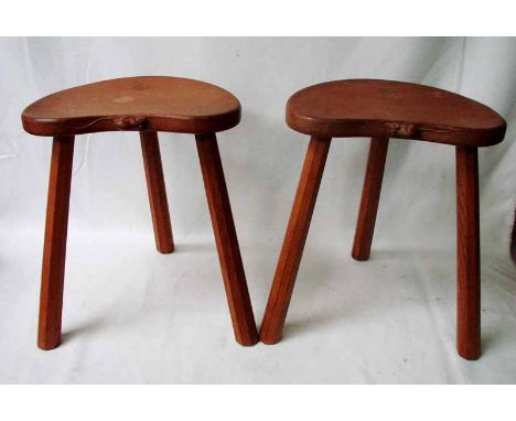 A pair of oak milking stools by Robert 'Mouseman' Thompson of Kilburn, three legged with kidney shaped seat carved to one sid