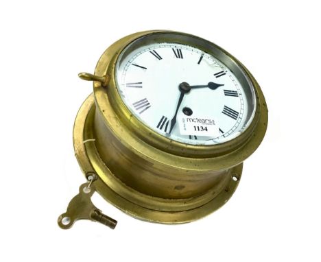 MID-20TH CENTURY SHIP'S BRASS CLOCK, with one train movement, the white enamel dial with Roman numerals, 21cm diameter