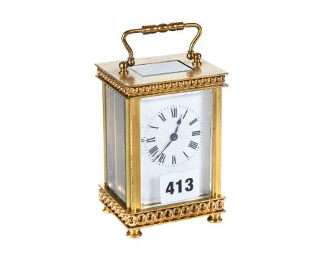AN EARLY 20TH CENTURY FRENCH BRASS 8 DAY CARRIAGE CLOCK with white enamel dial and chain link decoration, on turned feet, 4 1