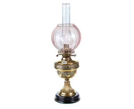A LATE VICTORIAN EMBOSSED BRASS TABLE OIL LAMP on a black pottery base, 11 ins high to burner.   £30-£50