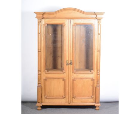 French pine cupboard, shaped top, shaped pediment with moulded cornice, glazed panel doors flanked by half columns, enclosing