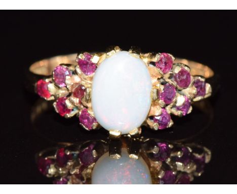 A 9ct gold ring set with an opal cabochon and rubies, 2.7g, size P