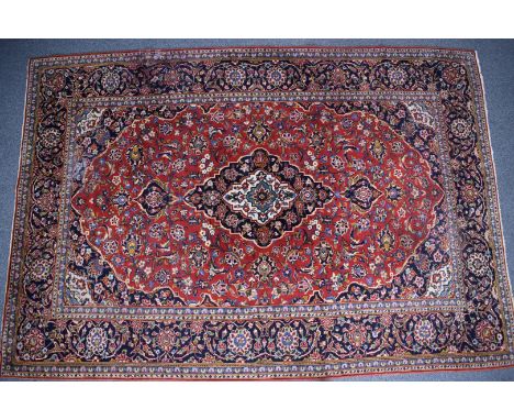 Large Persian carpet with central lozenge on a wine ground with navy border, 335 x 230cm