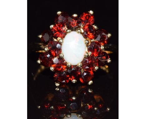 A 9ct gold ring set with an opal surrounded by garnets, 4.5g, size O