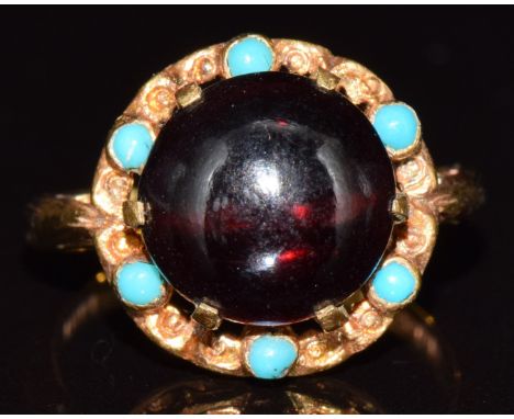 A 9ct gold ring set with a garnet cabochon surrounded by turquoise cabochons, 3.9g, size I