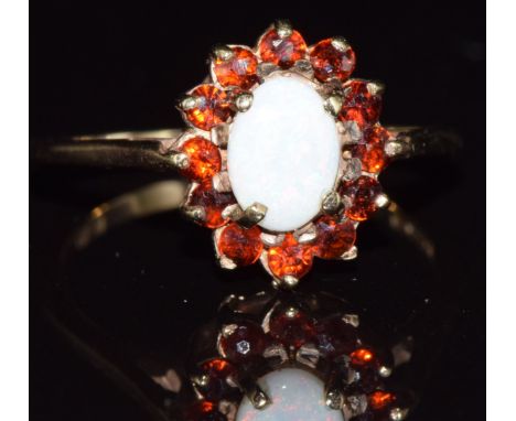 A 9ct gold ring set with an opal surrounded by garnets, 2.7g, size O