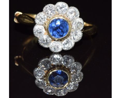 An 18ct gold ring set with a round cut sapphire of approximately 0.35ct surrounded by diamonds, each approximately 0.06ct, in