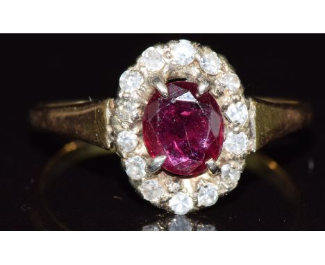 An 18ct gold ring set with an oval cut ruby surrounded by diamonds in a platinum setting, 3g, size O