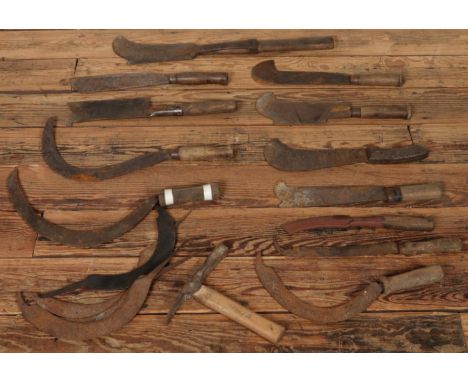 A collection of vintage bushcraft hand tools, including sickles, billhooks and others, all with wooden handles in various siz