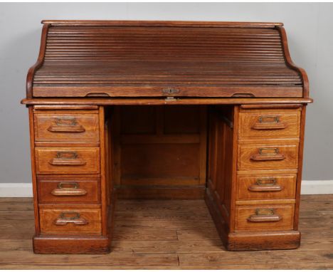 A mid Twentieth Century oak roll top desk, with panelled back, partial fitted interior and two banks of four drawers. Height: