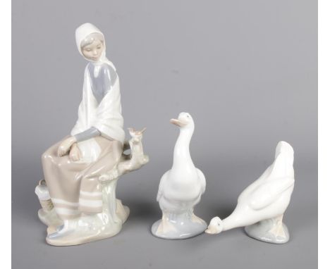 A Lladro ceramic figure depicting a girl with bird on branch along with two Nao by Lladro geese.