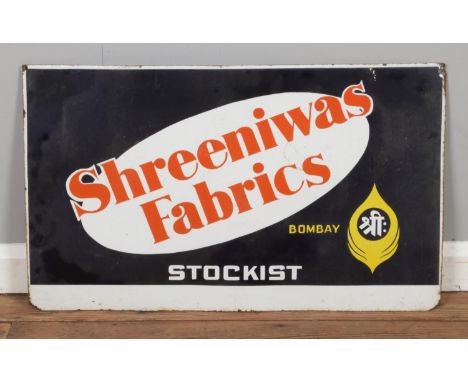 A vintage enamel sign, advertising Shreeniwas Fabrics, Bombay. Height: 46cm, Width: 76cm.  Some wear, mainly to edges. Drill 