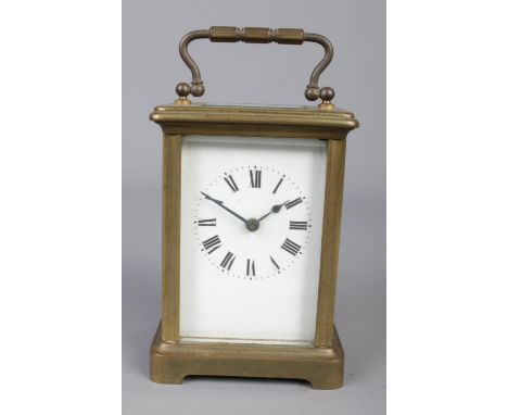 A brass carriage clock with bevelled glass panels, open escapement and Roman Numeral dial.  Key missing.