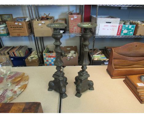 A pair of metal candlesticks on tripod feet, a/f