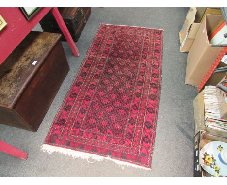 A Middle-Eastern wool rug in red and black tones, central panel of geometric design with multiple borders, worn, 173cm x 85cm