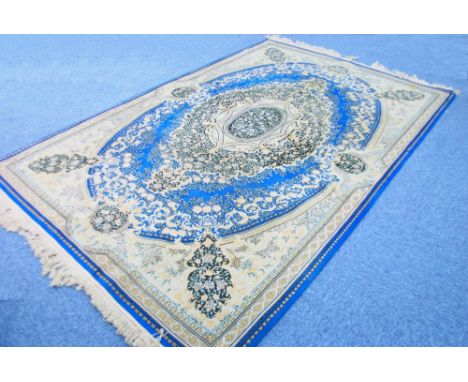 KIRMAN CARPET, principally dark blue and fawn having a large and elaborate floral centre medallion on a blue oval framed grou